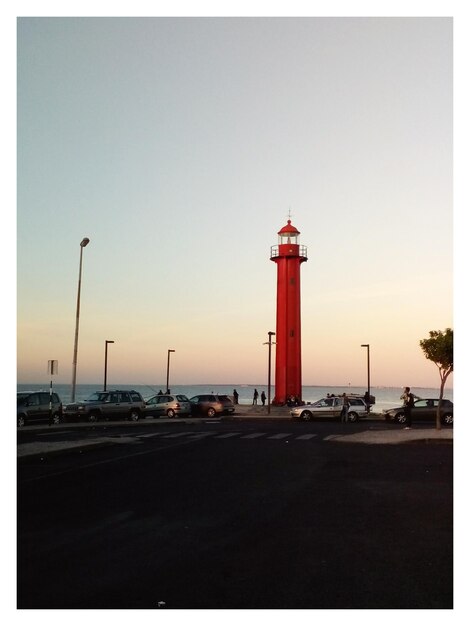 Foto faro por el mar contra un cielo despejado durante la puesta de sol