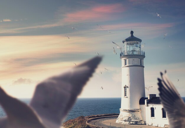 Faro por el mar contra el cielo durante la puesta de sol