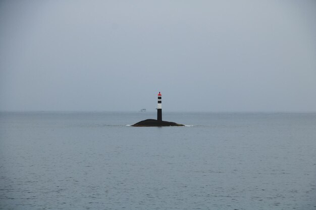 Foto faro por el mar contra el cielo