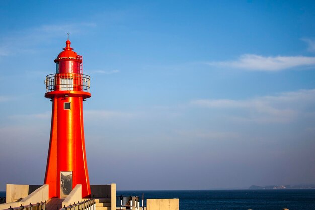 Foto faro por el mar contra el cielo