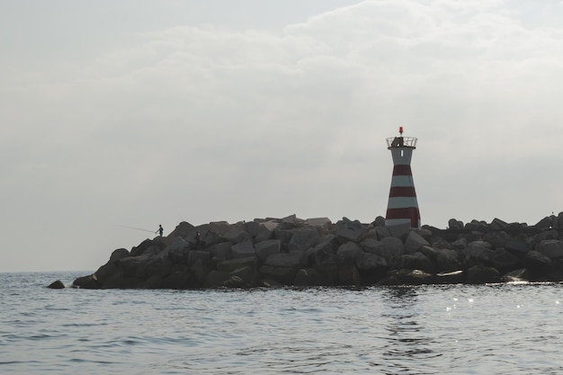 Foto faro por el mar contra el cielo