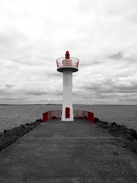 Foto faro por el mar contra el cielo