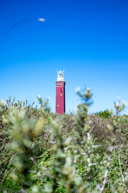 Foto faro por el mar contra el cielo