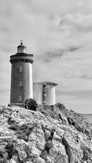 Foto faro por el mar contra el cielo