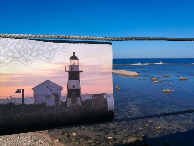 Foto faro por el mar contra el cielo