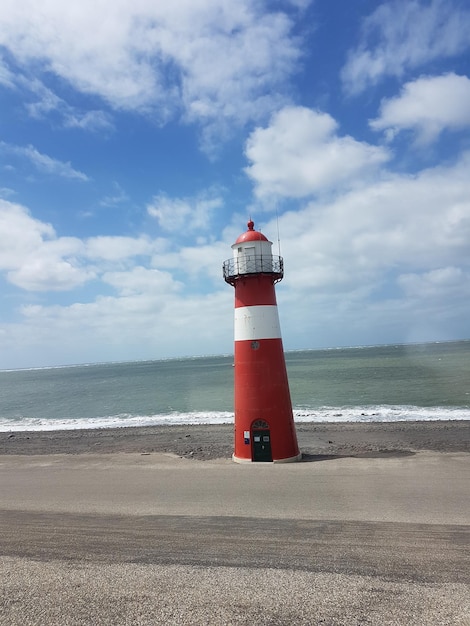 Foto faro por el mar contra el cielo