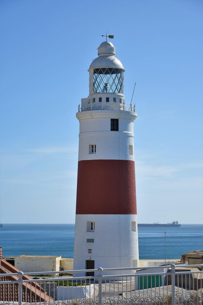 Foto faro por el mar contra el cielo