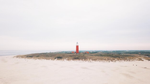 Foto faro por el mar contra el cielo