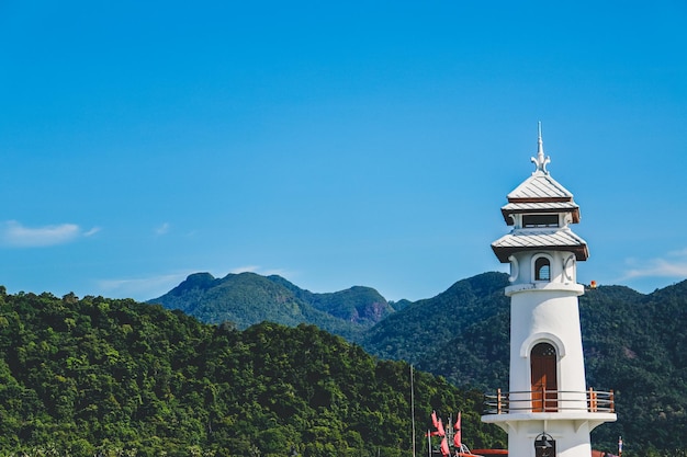 Faro con montaña y cielo despejado.