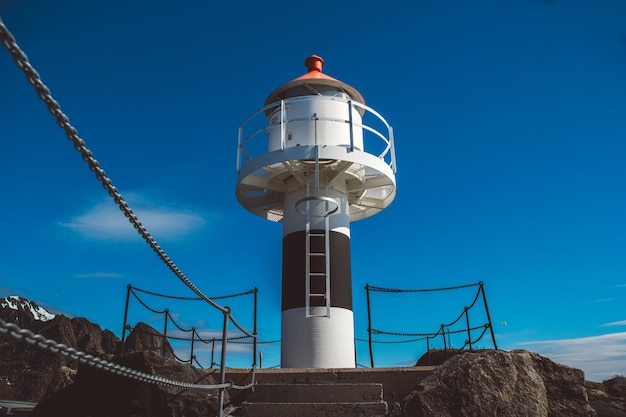 Faro en el muelle en el fondo de las montañas y el cielo azul de las islas Lofoten