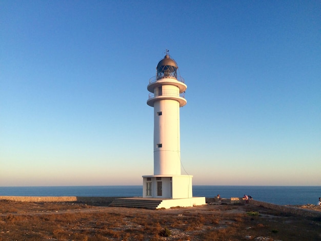 Faro en la orilla del mar contra un cielo azul claro