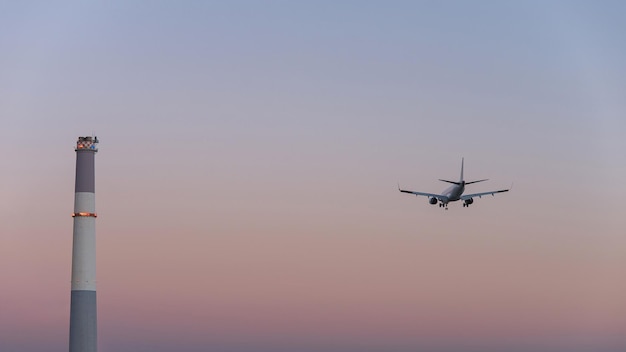 Foto un faro y un pequeño avión privado aterrizando o despegando con el fondo del cielo gris