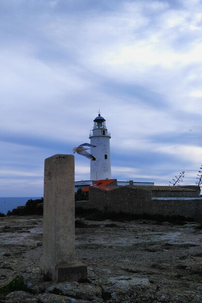 Foto faro en la playa contra el cielo nublado