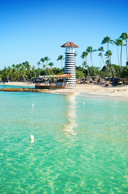 Faro de rayas en la orilla arenosa con palmeras. Agua clara del mar Caribe.