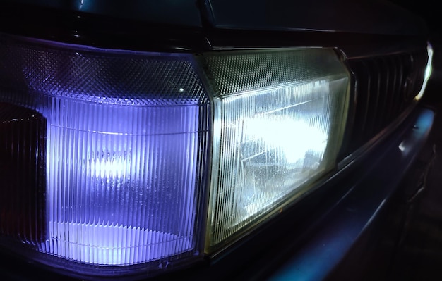 Faro rectangular de bule coche con luces encendidas en la carretera oscura vista cercana