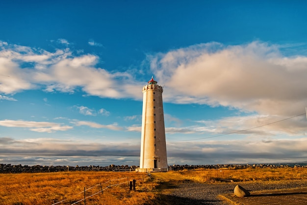 Faro en reykjavik, islandia. Torre del faro en el campo del otoño en el cielo azul nublado. Estructura y diseño. Concepto de ayuda a la navegación.