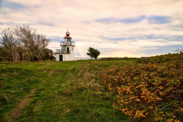 Faro Spodsbjerg Fyr en Huntsted en la costa de Dinamarca Rayos de sol brillando