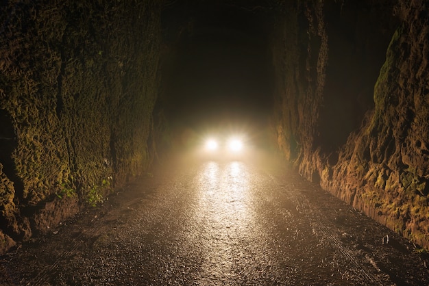 Faróis de carros à noite na estrada nevoenta