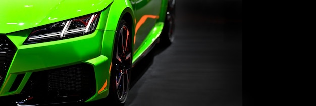 Faróis dianteiros de um carro esportivo moderno verde em um fundo preto com espaço livre no lado direito para texto