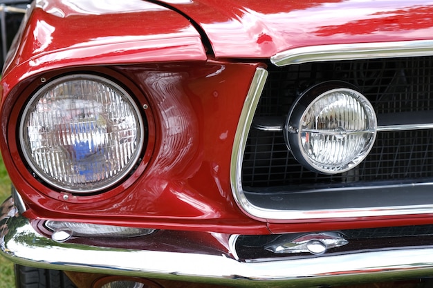 Faróis, radiador e capô de close-up retrô carro vermelho.