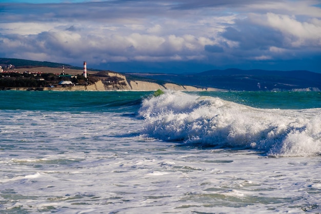 Farol de Gelendzhik em uma tempestade no Mar Negro Salpica ondas em rochas e montanhas