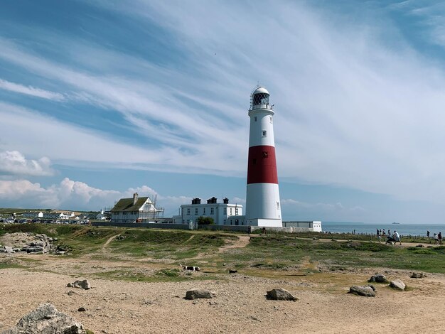 Foto farol de portland bill pelo mar contra o céu ligeiramente nublado e o mar