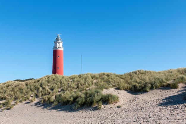 Farol de Texel sobre as dunas com um céu azul claro