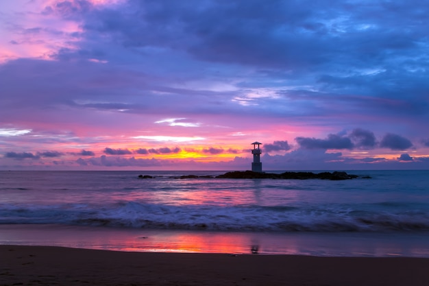 Farol do pôr do sol nas rochas na costa do mar.