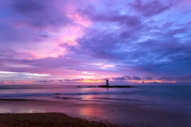 Farol do pôr do sol nas rochas na costa do mar.