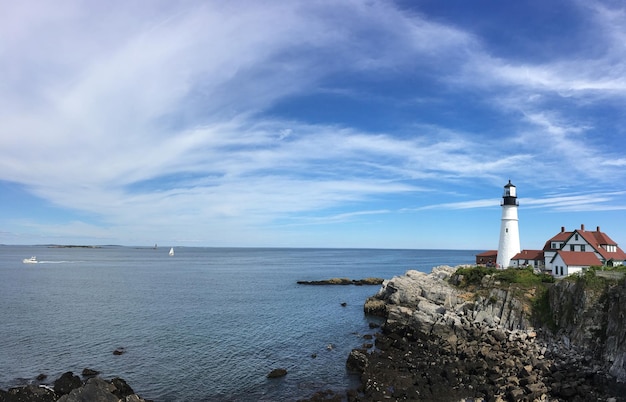 Farol em formação rochosa no mar contra o céu