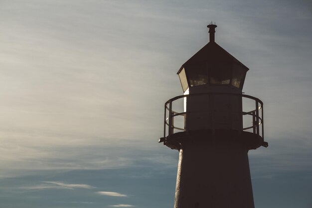 Farol em silhueta ao pôr do sol e céu dramático. Lugar para texto ou publicidade