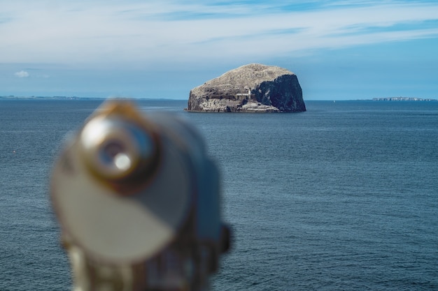Farol em um penhasco e há um telescópio de desfoque em primeiro plano. Bass Rock, Escócia, Reino Unido