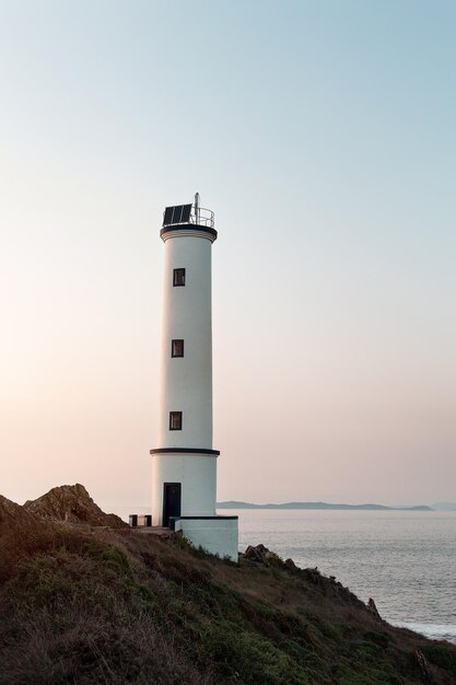 Farol na costa ao pôr-do-sol