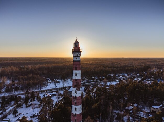 Foto farol na costa do lago iluminado pelos raios do sol da noite fotografia aérea