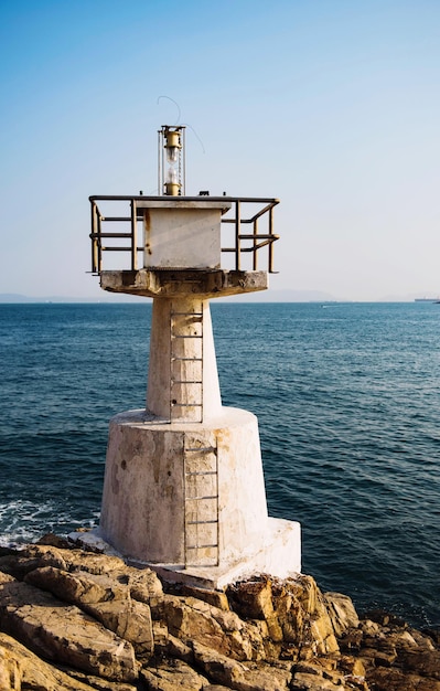 Farol na costa rochosa contra o céu em um dia ensolarado