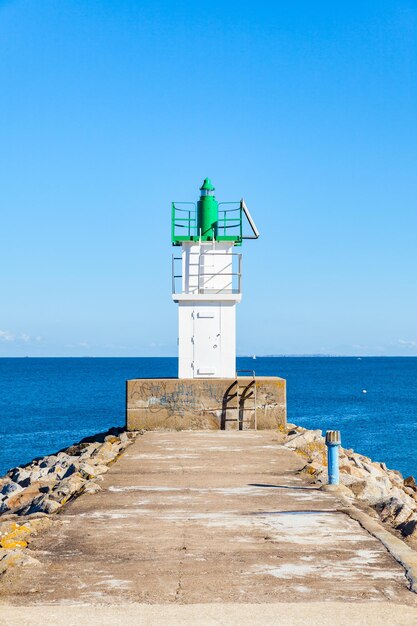 Foto farol pelo mar contra o céu azul claro