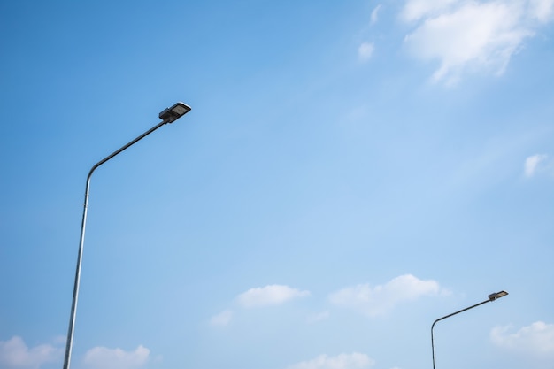 Farola LED en poste de acero con cielo azul y nubes.