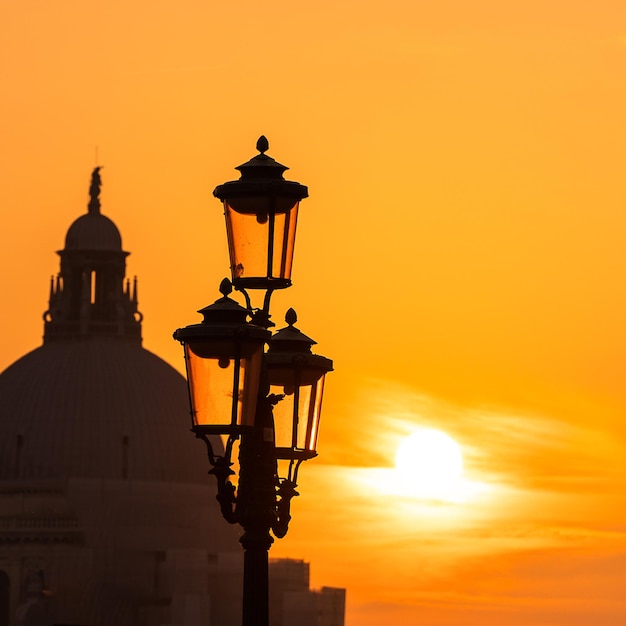 Farola de Venecia al atardecer con la Basílica de Santa Maria della Salud al fondo