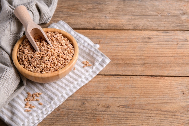 Farro de espelta cruda cruda integral en un tazón en el fondo de madera