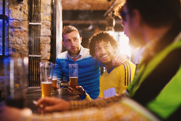 Fãs de diferentes clubes de futebol estão tendo uma discussão amigável sobre qual time é melhor em um pub local.