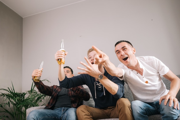 Fãs de esportes de amigos assistindo a uma partida de futebol vitoriosa na TV em casa