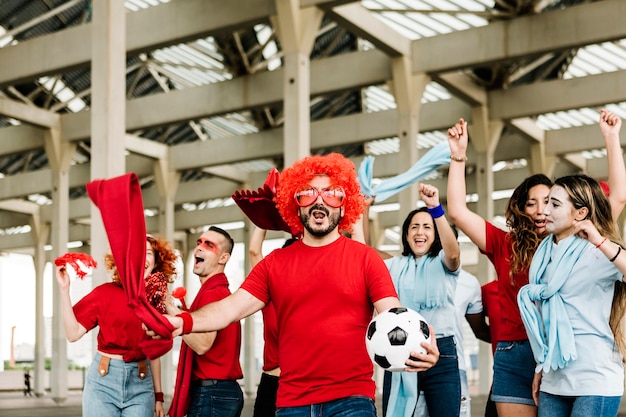 Fãs de esportes multirraciais felizes se divertindo fora do estádio