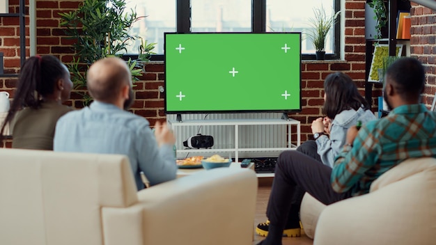 Fãs de futebol assistindo jogo de futebol usando tela verde na televisão, desfrutando de torneio de jogos esportivos em copyspace isolado. Olhando para o modelo de maquete em branco e plano de fundo na tv.