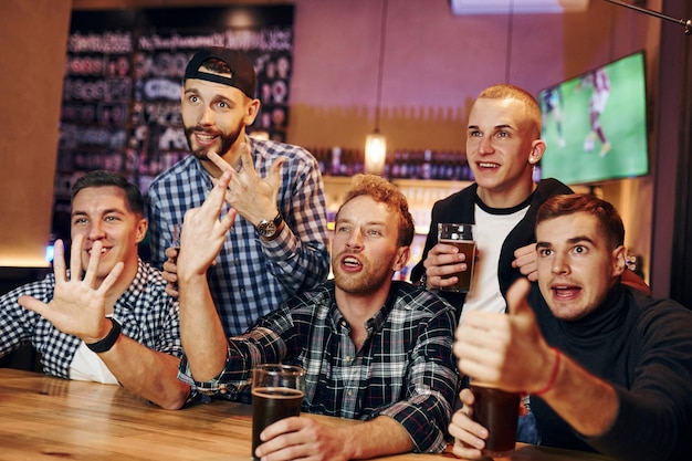 Fãs de futebol assistindo TV Grupo de pessoas juntas no pub se divertem no fim de semana