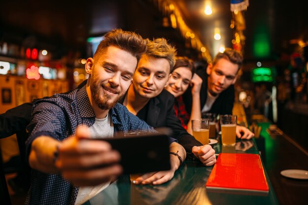 Fãs de futebol felizes fazem selfie no telefone no balcão de um bar esportivo, comemoração da vitória