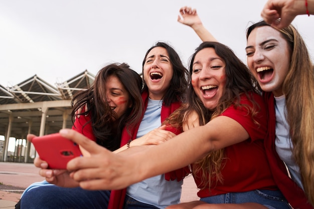 Fãs de futebol olhando para o telefone durante a partida de futebol