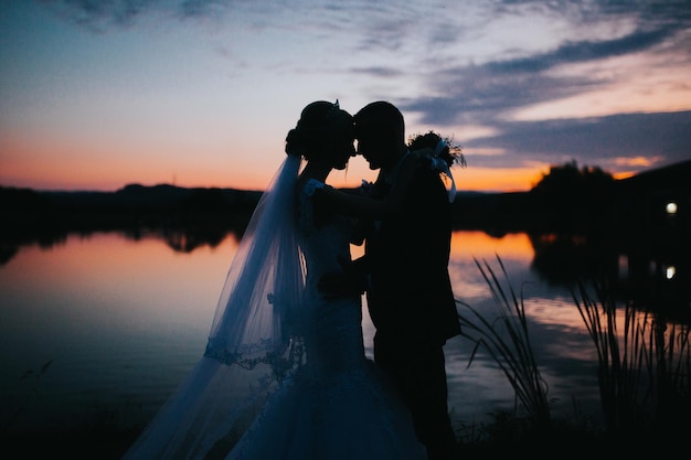 Fascinante foto de una pareja el día de la boda en el hermoso fondo de la puesta de sol