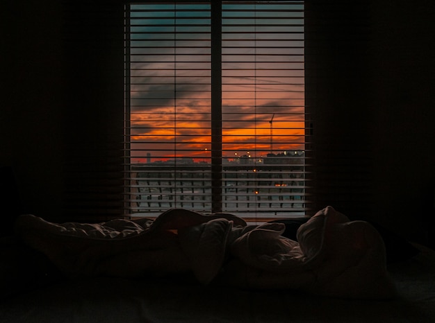 Fascinante vista de la puesta de sol atravesando el cielo nublado desde las persianas de la ventana