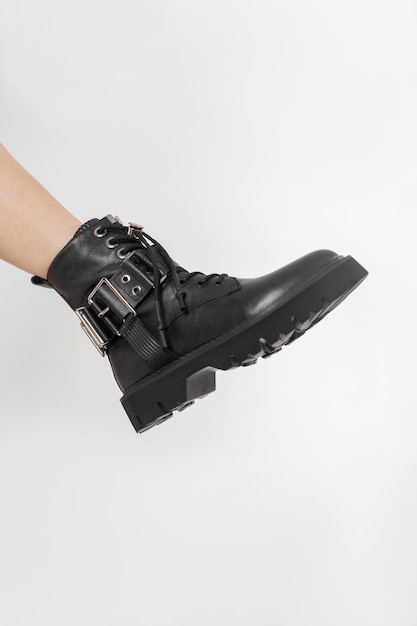 Fashion cool schwarz Leder Damenschuhe auf weißem Hintergrund Weibliches Bein mit trendigen Boot im Studio