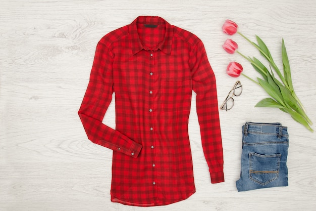 Fashion-Konzept. Rote Bluse, Jeans, Lippenstift und rosa Tulpen. Ansicht von oben